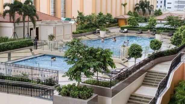 Ett hotell med en central pool omgiven av grönska och en trappa som leder upp till de övre våningarna.