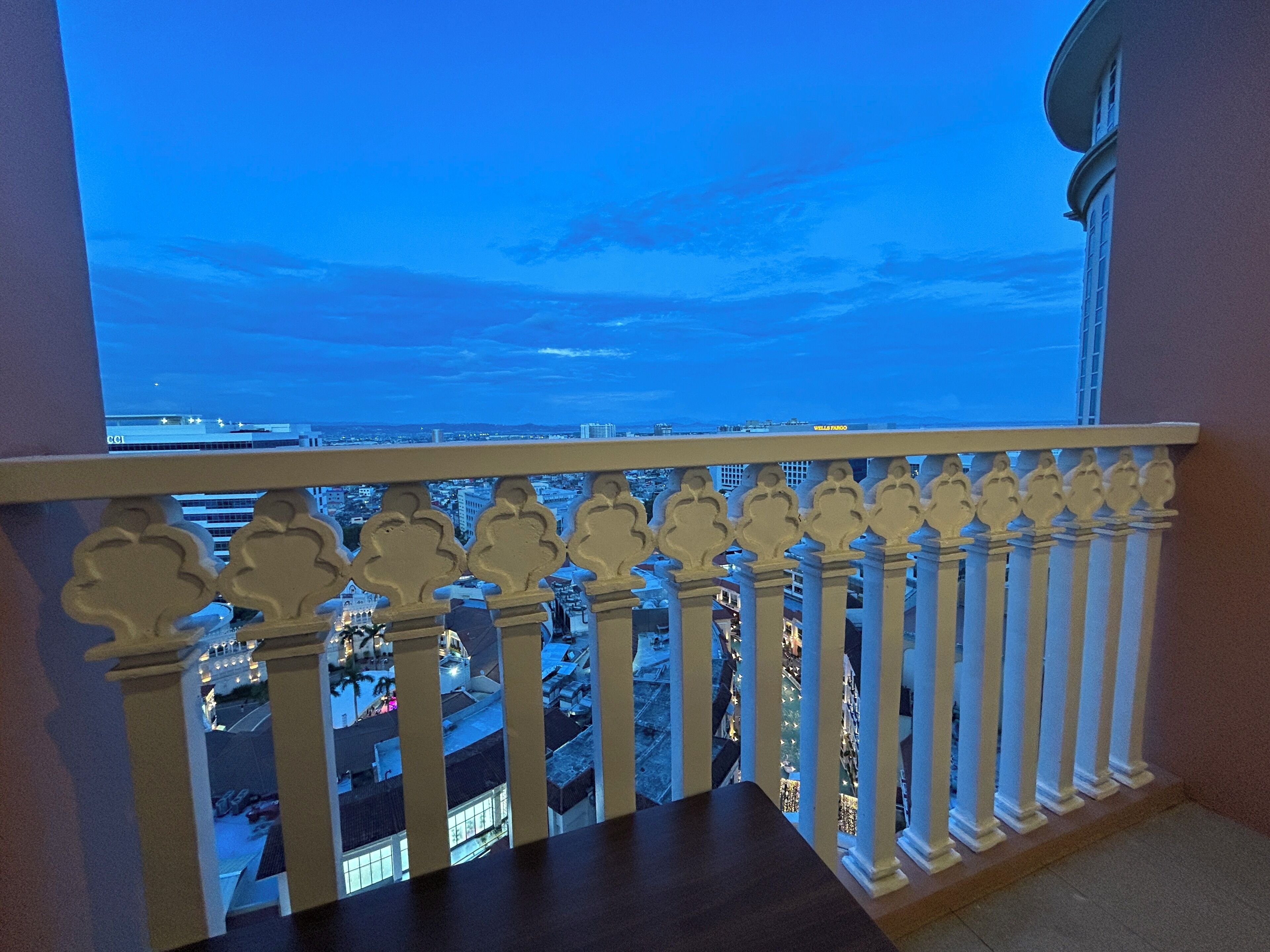 A balcony with a view of a cityscape at dusk.