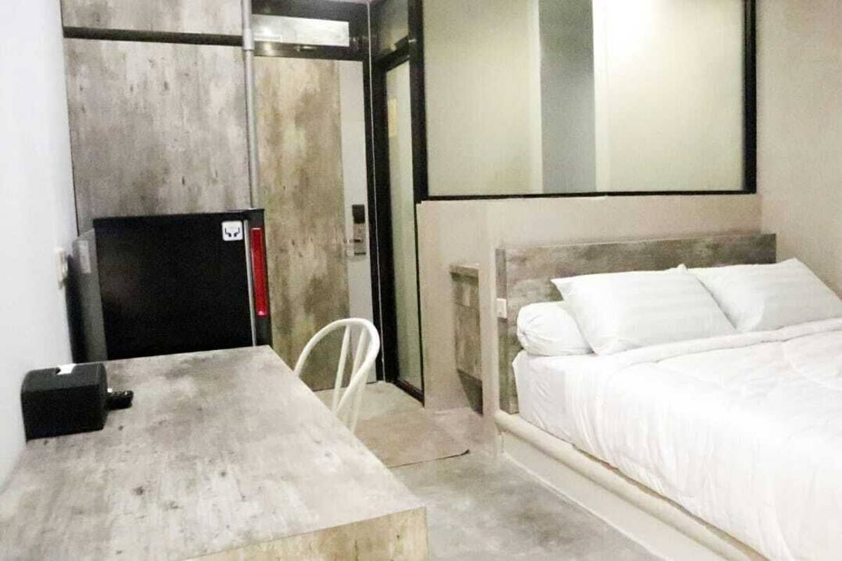 A compact hotel room with a single bed, a small table, a chair, and a built-in desk.