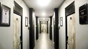 A long, narrow hotel corridor with doors on both sides, each marked with a sign indicating the hotel name and affiliation. - D'Paragon Beo (Depok)