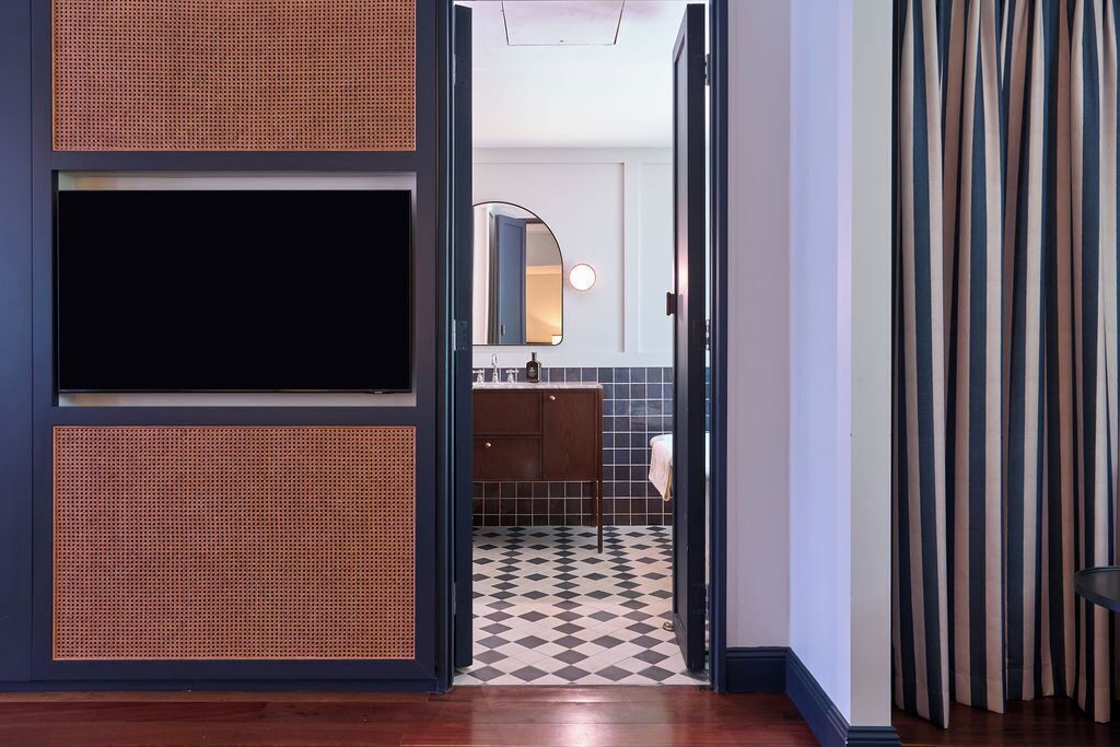 A modern bathroom with a black and white checkered floor, a wooden cabinet, and a mirror above the sink.