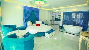 A modern hotel room with a large bed, a sitting area with chairs, a bathtub, and a kitchenette. - The Lion Kingdom Sigiriya (Dambulla)