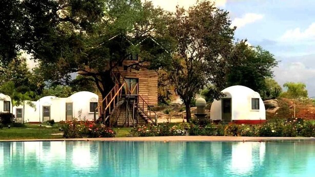 A pool area with several white mobile homes, surrounded by trees and a wooden structure. - The Lion Kingdom Sigiriya (Dambulla)