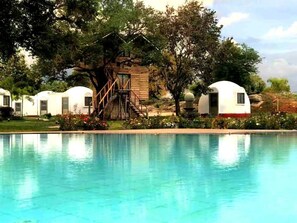Un área de piscina con varias casas móviles blancas, rodeada de árboles y una estructura de madera.