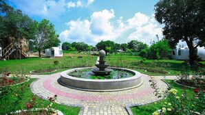 A circular garden with a central fountain, surrounded by a brick pathway and flower beds. - The Lion Kingdom Sigiriya (Dambulla)