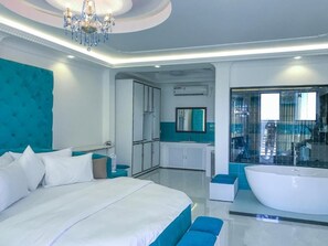 Una habitación de hotel moderna con una cama grande, una bañera y un área de baño separada.