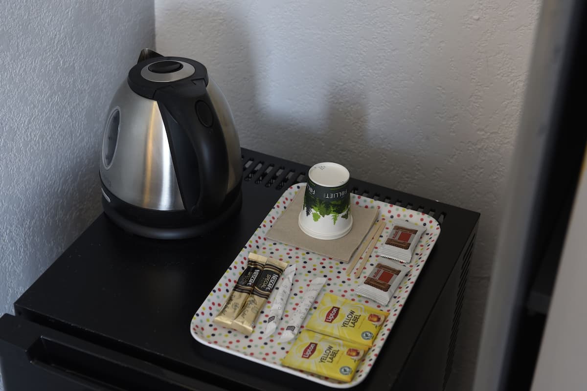 A small table with a kettle, a mug, and a tray with food items.