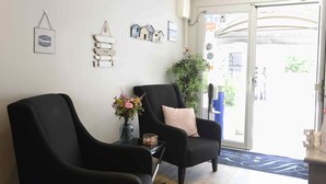 A reception area with two black armchairs, a vase with flowers, and wall decorations including framed pictures and a sign. - Azur Hotel (Balaruc-les-Bains)