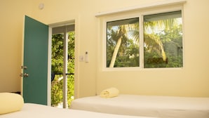 A room with a bed, a window with a view of trees, and a door leading outside. - Inn at Tamarind Court (St. John)