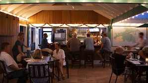 A restaurant with wooden walls and a bar area. There are tables and chairs for dining, and a map is displayed on the wall. - Inn at Tamarind Court (St. John)