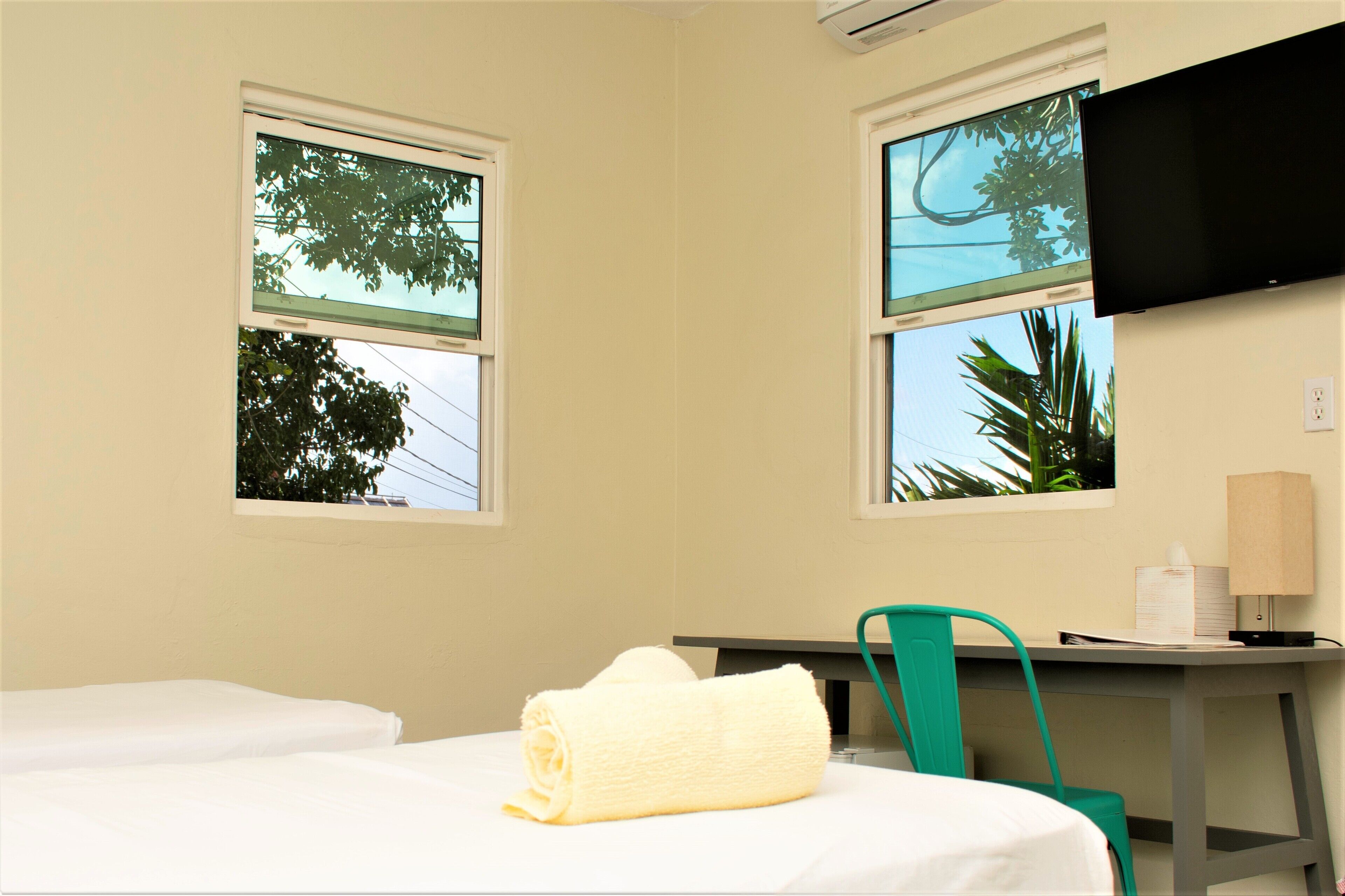 A hotel room with two beds, a desk, a chair, and a TV mounted on the wall.