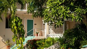 A building with a green door, white railings, and a staircase leading to a balcony. - Inn at Tamarind Court (St. John)