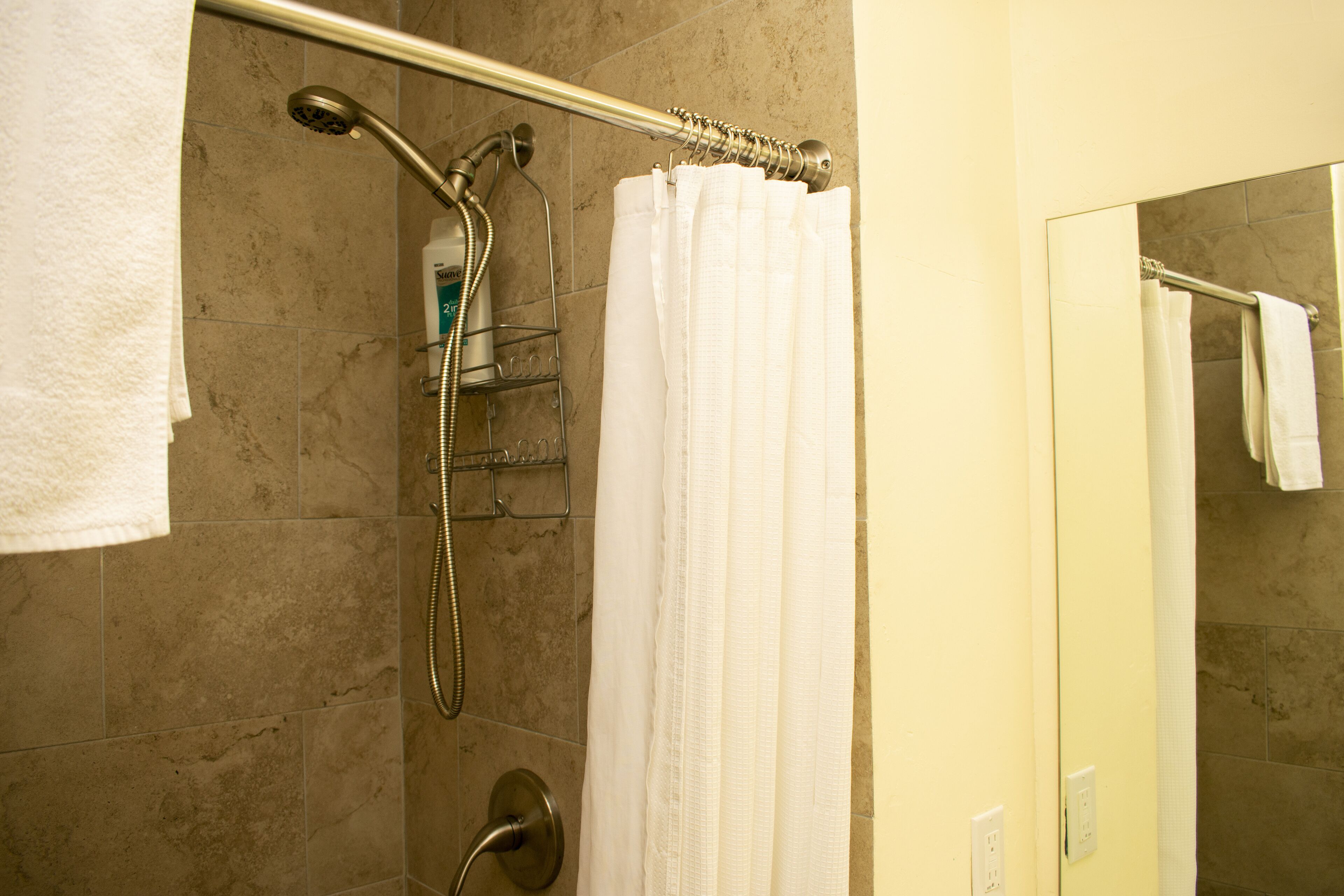 A bathroom with a shower, a towel rack, and a shower caddy.