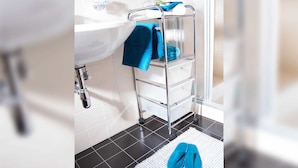 A bathroom with a white sink, chrome faucet, and a towel rack with folded towels.