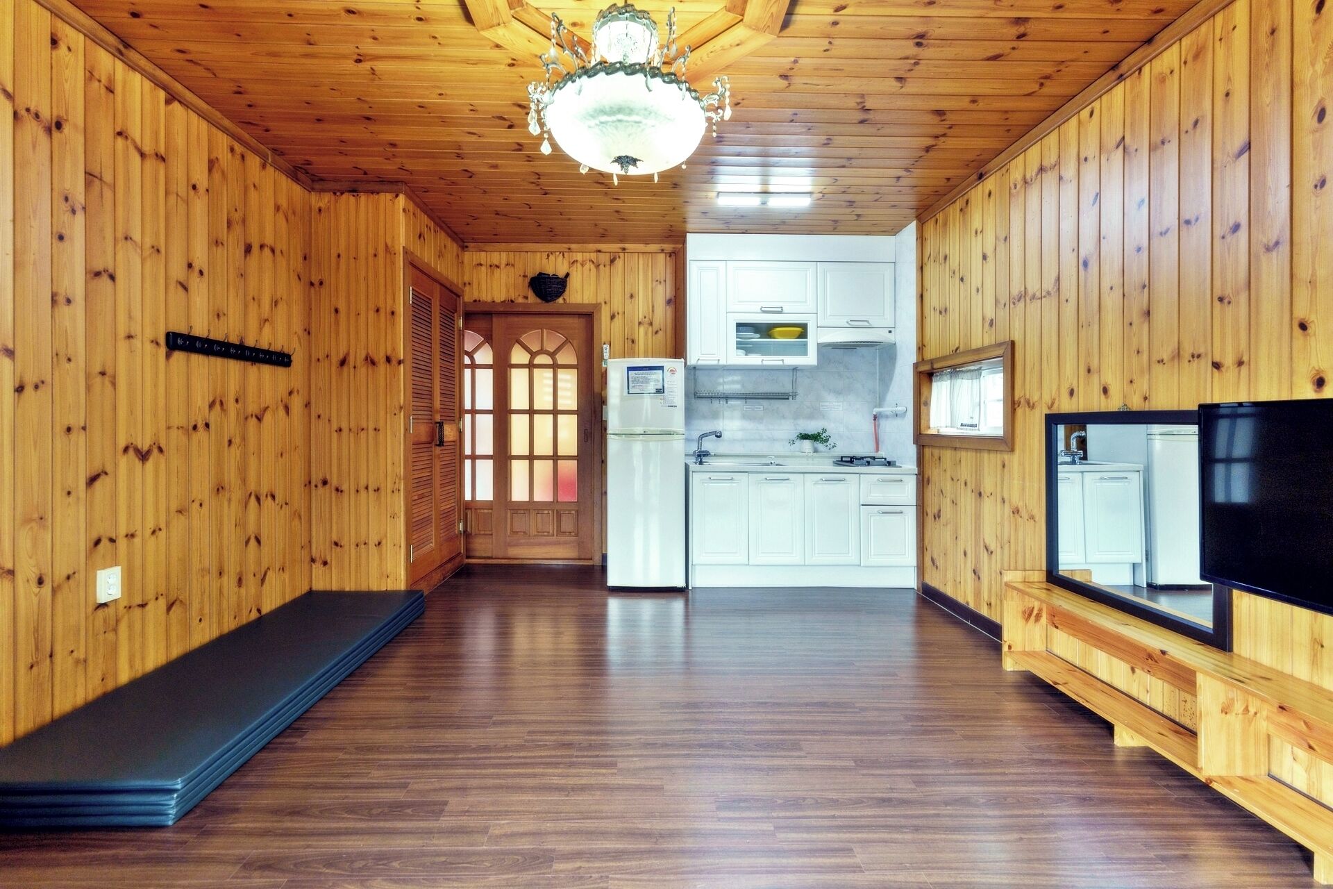 A wooden interior with a kitchen area, a dining area, and a living room with a TV.