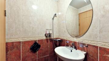 Un baño con lavamanos blanco, un espejo y una ducha.