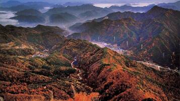 A mountainous landscape with winding roads and a distant view of a town.