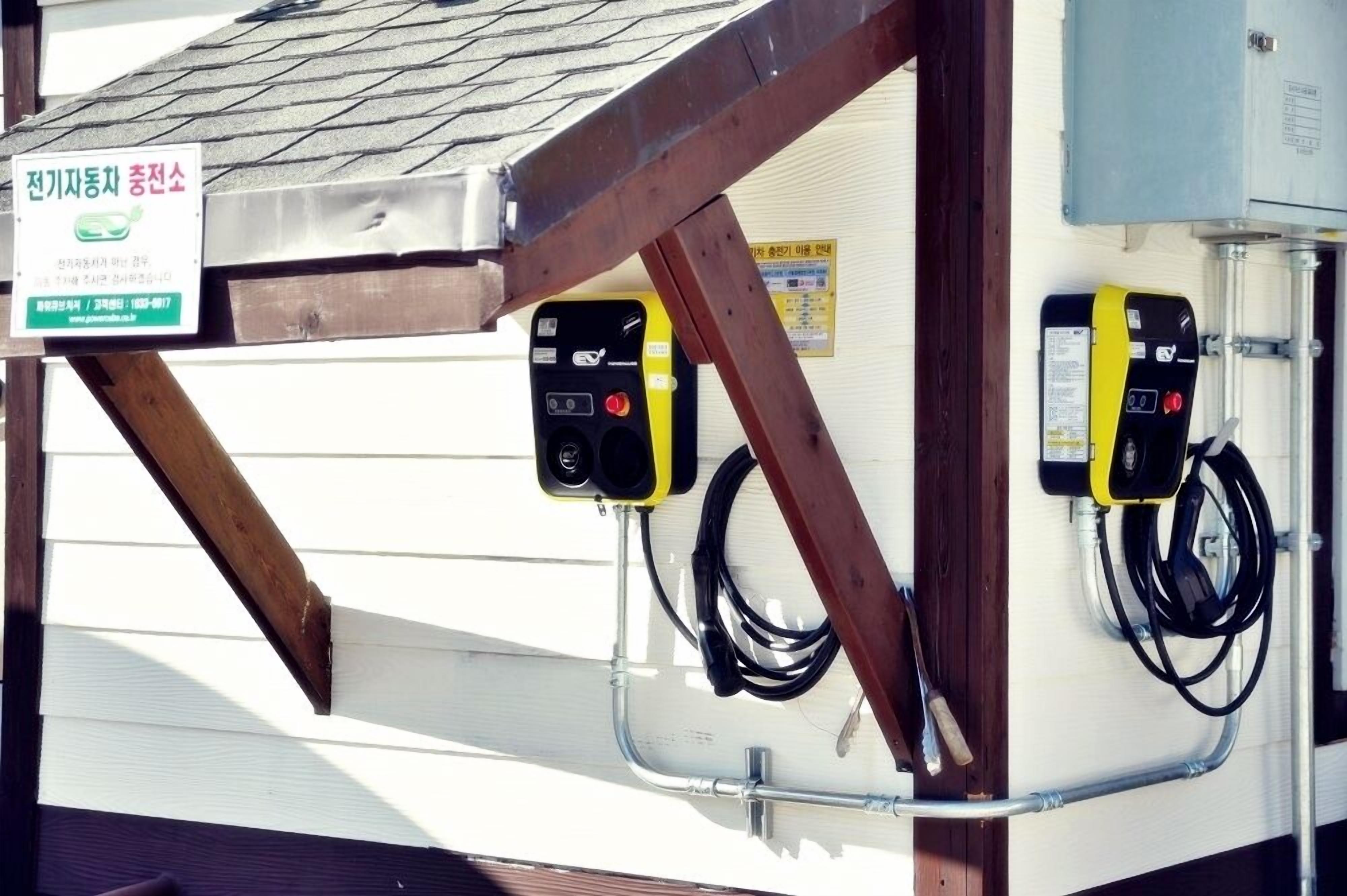 Un compteur d’électricité avec une inscription en coréen, une structure en poutres de bois et des câbles électriques.