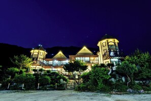 A large, multi-story hotel with a prominent tower and a covered patio area. - Muju Cherish Pension (Muju)