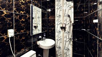 Un bagno con WC, lavandino e doccia. Le pareti presentano un motivo marmorizzato nero e oro.