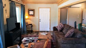A cozy living room with a ceiling fan, a television, a sofa, and a coffee table. - Mountain Majesty (Ruidoso)