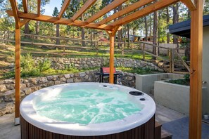 Un jacuzzi bajo una pérgola de madera en un jardín ajardinado.