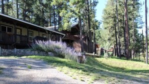A rustic cabin with a stone foundation, wooden exterior, and a porch with railings. - Friendly Nabors (Ruidoso)