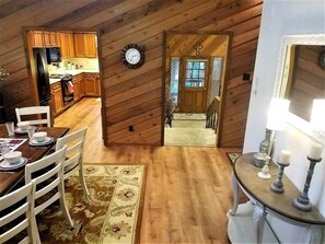 A wooden interior with a dining area, kitchen, and a clock on the wall. - Mountain Memories (Ruidoso)