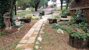 Ein Gartenweg führt zu einem Gebäude mit Holzzaun und einer Statue.