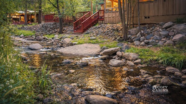 Une cabane avec une façade en bois, un sentier pavé de pierres et un petit ruisseau.