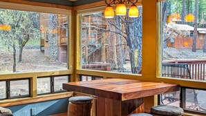 Un bar en bois doté de grandes fenêtres donnant sur une zone boisée.