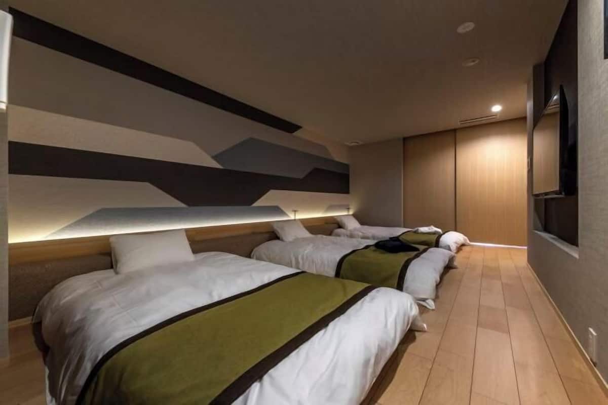 Una habitación de hotel con dos camas, un diseño moderno en la pared y un televisor.