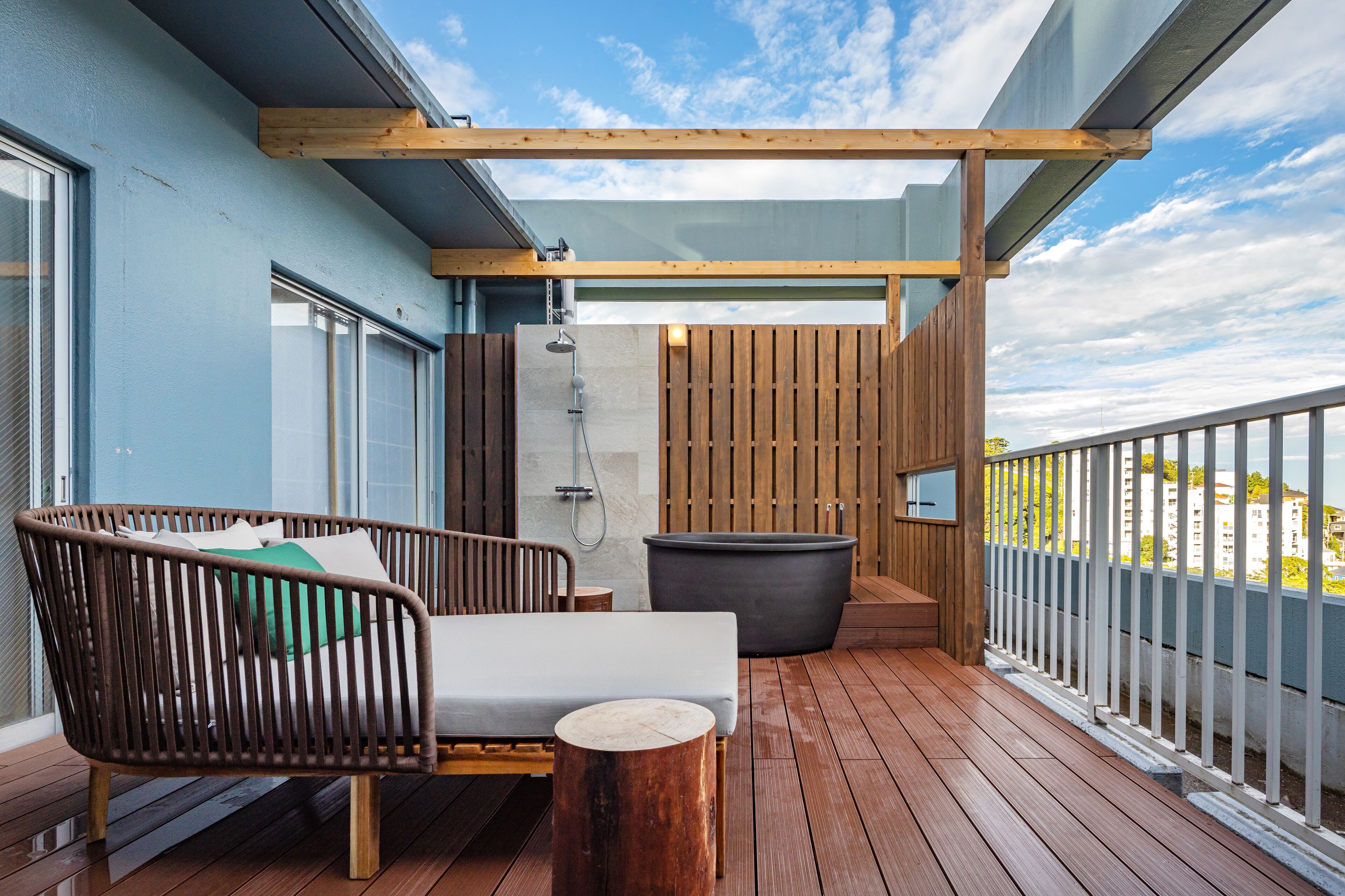 Una terraza de madera con un sofá, una mesita y una bañera grande.