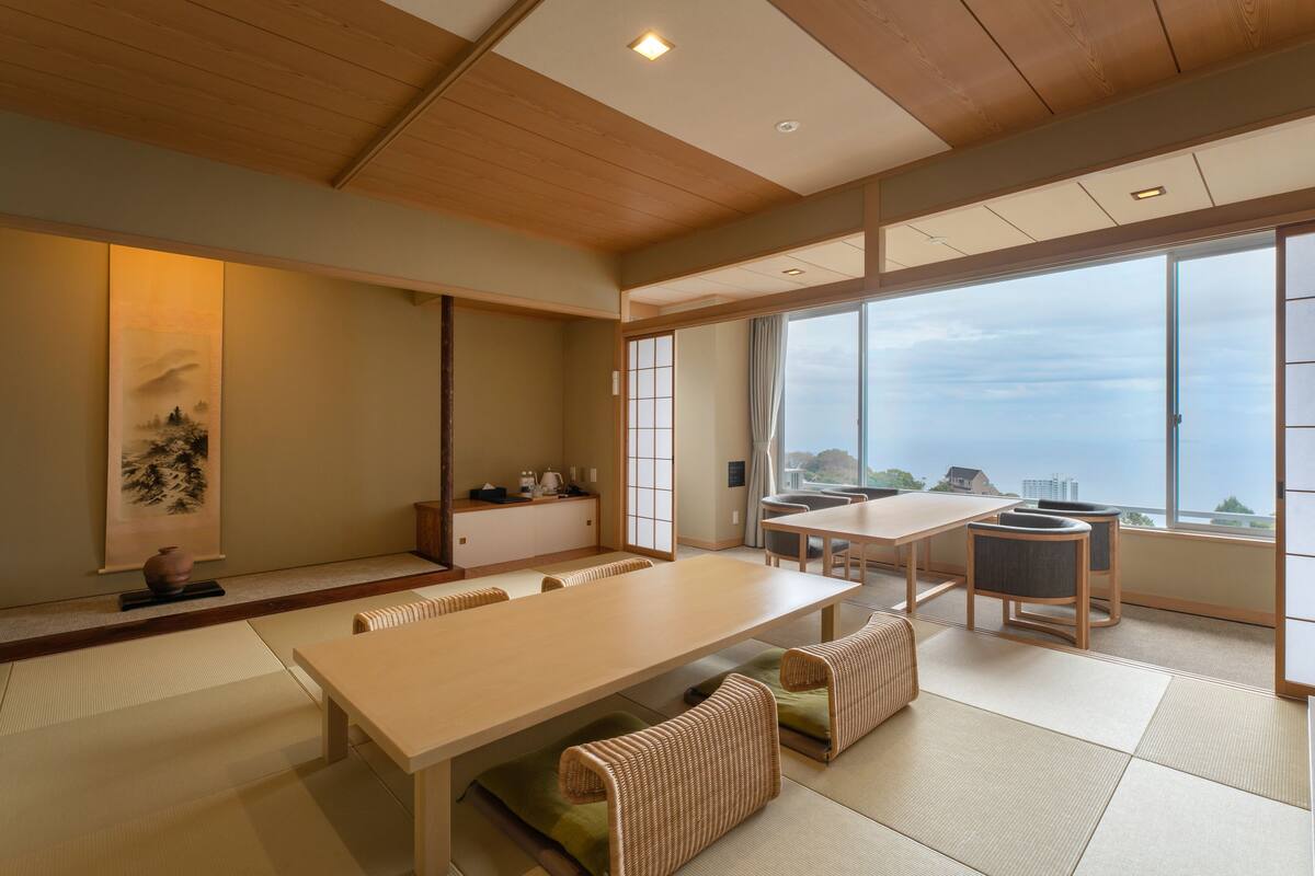 A traditional Japanese-style room with tatami flooring, a low table, and a view of the sea.