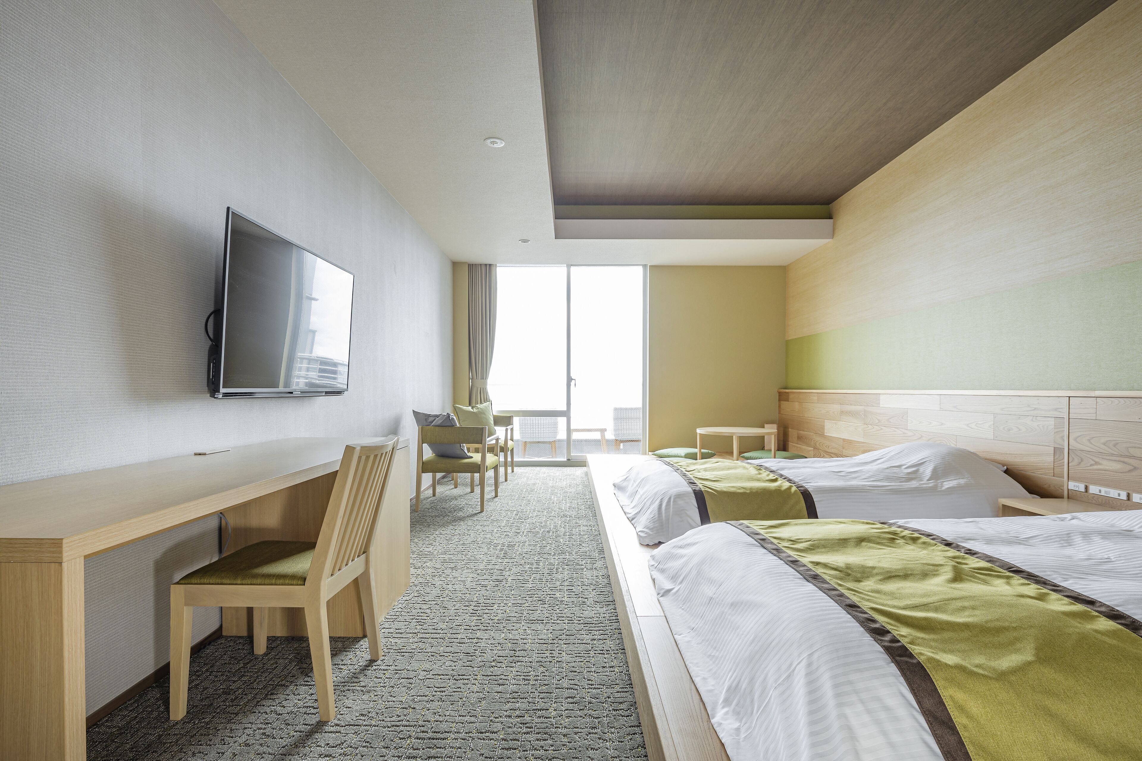 A hotel room with a bed, a desk, a chair, a television, and a view of the outdoors.