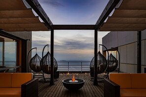 A wooden deck with a fire pit, wicker chairs, and a view of the ocean. - Ishinoya Atami (TKP Hotels & Resorts) (Atami)