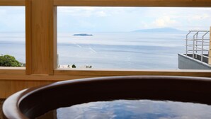 A view from a wooden-framed window overlooking a calm sea with a distant island and a ship. - Ishinoya Atami (TKP Hotels & Resorts) (Atami)