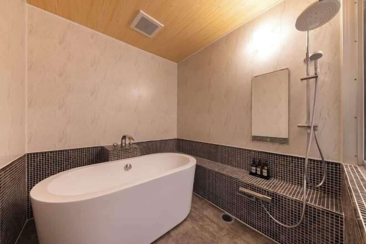 Un baño moderno con una bañera independiente, cabezal de ducha y salpicadero de azulejos.