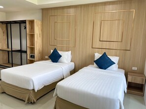 Habitación de hotel con dos camas, paneles de madera en las paredes y un armario empotrado con estantes.