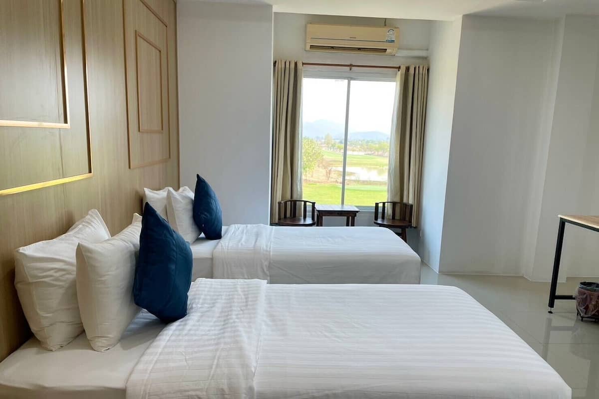 Une chambre d’hôtel avec deux lits, une vue sur un terrain de golf et un système de climatisation.