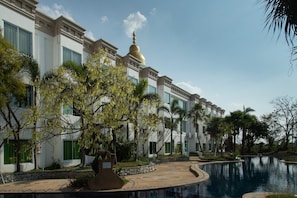 A hotel with a pool, palm trees, and a building with a golden dome.