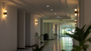 A modern hotel corridor with recessed lighting, potted plants, and a glass door at the end. - Gassan Panorama Golf Club (Ban Thi)