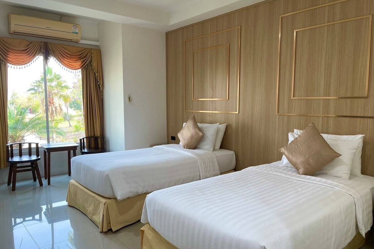 Une chambre d’hôtel avec deux lits, un bureau et une vue sur les palmiers.