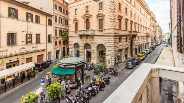 A historic building with a central courtyard, surrounded by parked scooters and cars. - Romantico by Interhome (Rome: Historical City Center)