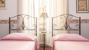 A bedroom with two beds, a small table with a lamp, and curtains. - Romantico by Interhome (Rome: Historical City Center)