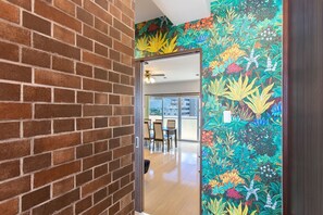 A hallway with a brick wall and a colorful floral mural on the right.