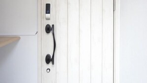 A white door with a modern handle and a small electronic device mounted on the wall above it. - Sakura 612 (Sapporo)