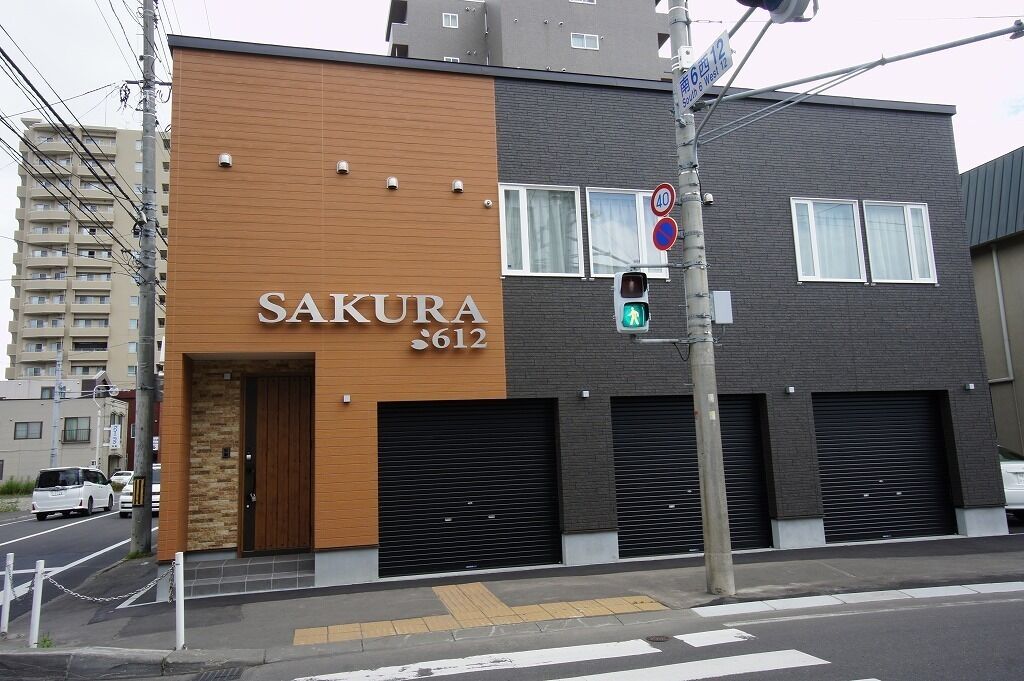 A building with a sign reading "SAKURA 612" and a green traffic light.
