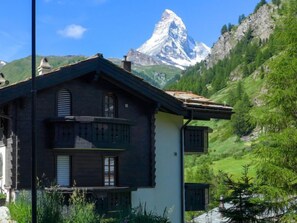 Een klassiek chalet met een balkon, met op de achtergrond een bergtop.