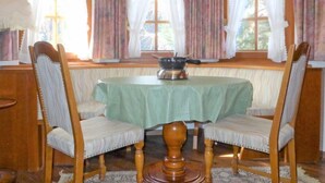 Une salle à manger avec une table ronde, deux chaises et une fenêtre avec des rideaux.